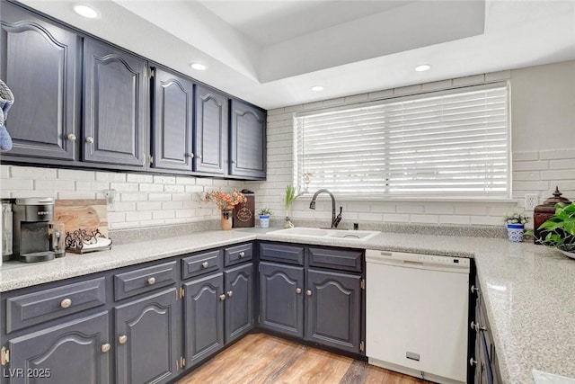 kitchen featuring white dishwasher, a wealth of natural light, a sink, and tasteful backsplash