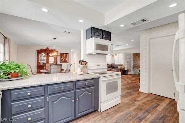 kitchen featuring visible vents, wood finished floors, light countertops, open floor plan, and white appliances