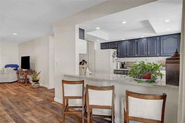 kitchen featuring recessed lighting, freestanding refrigerator, baseboards, and a peninsula