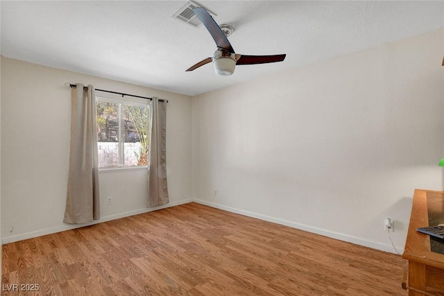 spare room featuring baseboards, a ceiling fan, wood finished floors, and visible vents