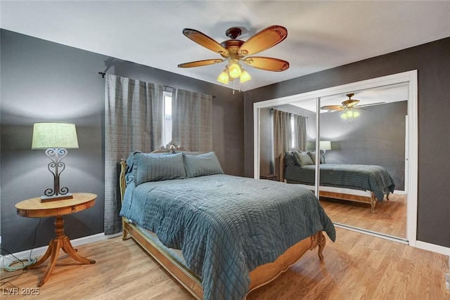 bedroom with a closet, light wood-style flooring, ceiling fan, and baseboards