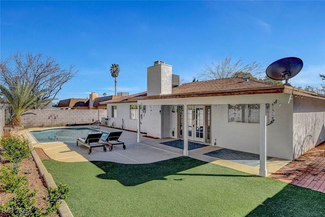 rear view of house with a fenced backyard, stucco siding, french doors, a chimney, and a patio area