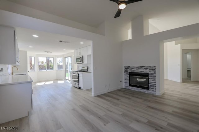 4416 Inez Dr, Las Vegas, NV 89130 - unfurnished living room with a ceiling fan, a stone fireplace, a sink, and light wood finished floors
