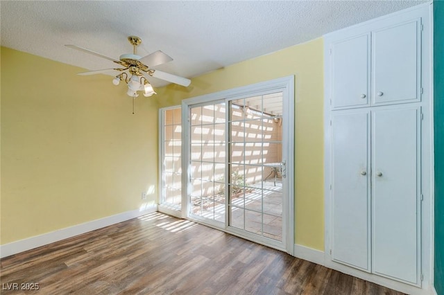 interior space with baseboards, access to outside, a textured ceiling, and dark wood-type flooring