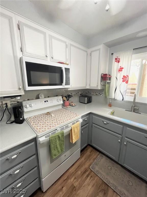 kitchen with white appliances, light countertops, gray cabinets, a sink, and dark wood finished floors