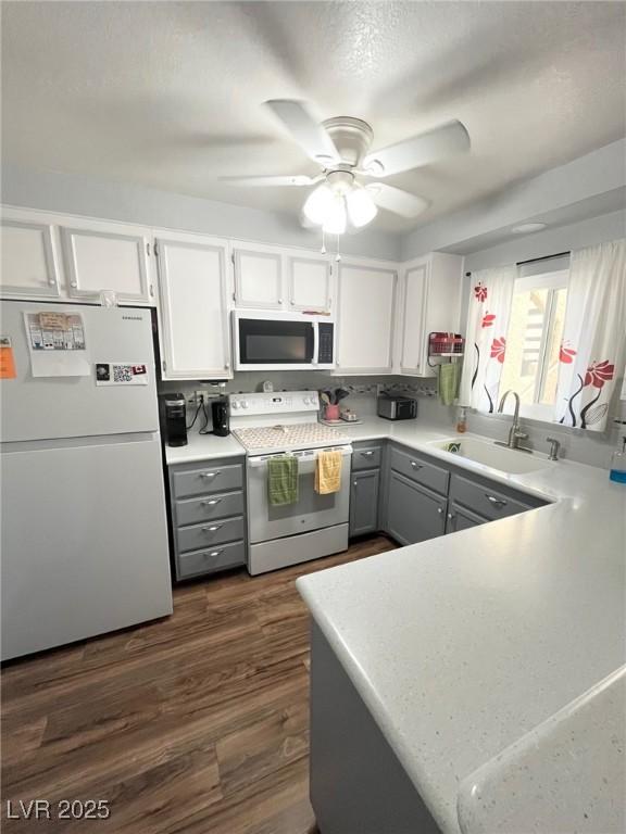 kitchen featuring a ceiling fan, white appliances, light countertops, a sink, and gray cabinetry
