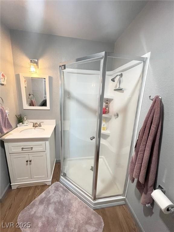 bathroom featuring vanity, a stall shower, baseboards, and wood finished floors