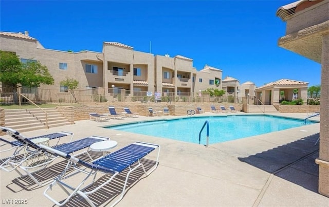 community pool featuring fence, a residential view, and a patio area