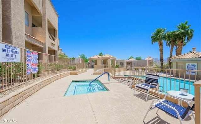 community pool featuring a patio, a hot tub, and fence