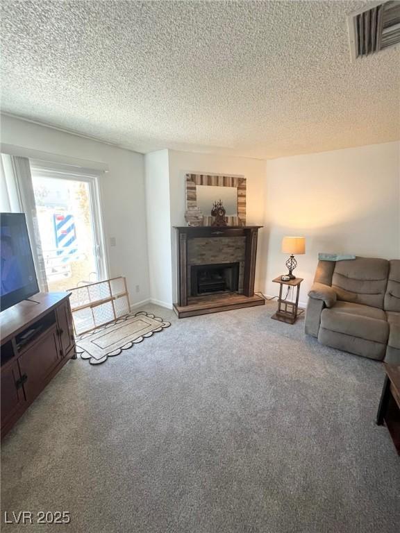 carpeted living room with a fireplace with raised hearth, a textured ceiling, and visible vents