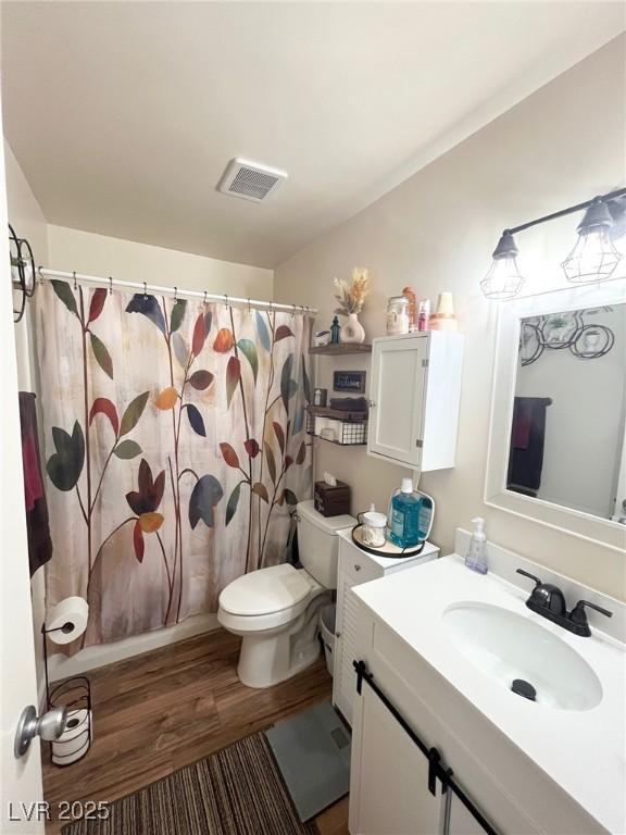 full bathroom featuring a shower with curtain, visible vents, wood finished floors, vanity, and toilet
