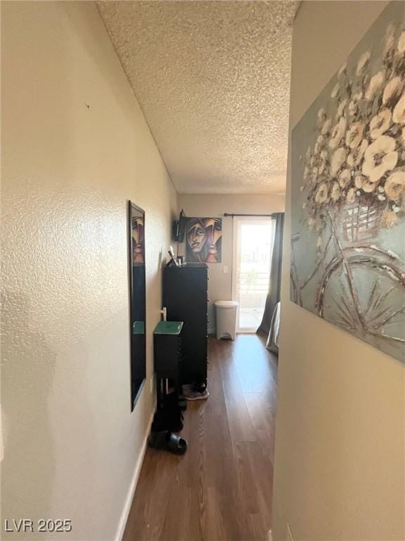 hallway with a textured ceiling and wood finished floors