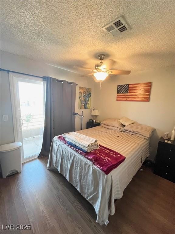 bedroom with access to outside, a textured ceiling, visible vents, and wood finished floors