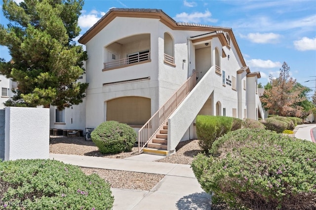 view of building exterior featuring a garage, stairway, and central AC unit