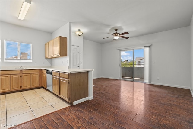 kitchen with stainless steel dishwasher, a peninsula, open floor plan, ceiling fan, and light countertops