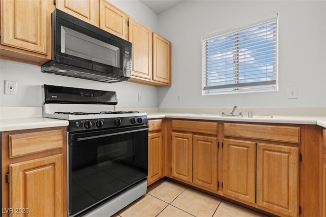 kitchen featuring black microwave, gas range, light countertops, a sink, and light tile patterned floors