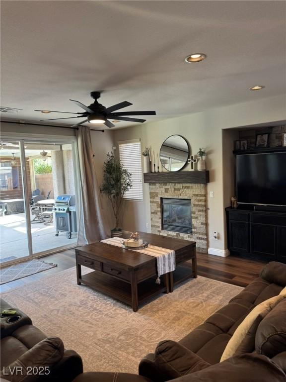 living area featuring a ceiling fan, a fireplace, wood finished floors, baseboards, and recessed lighting