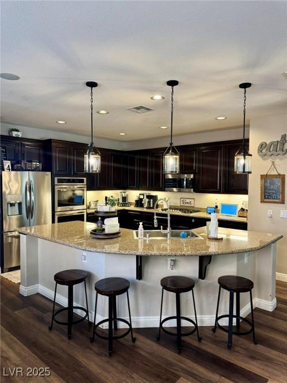 kitchen with stainless steel appliances, a large island, visible vents, and dark wood finished floors