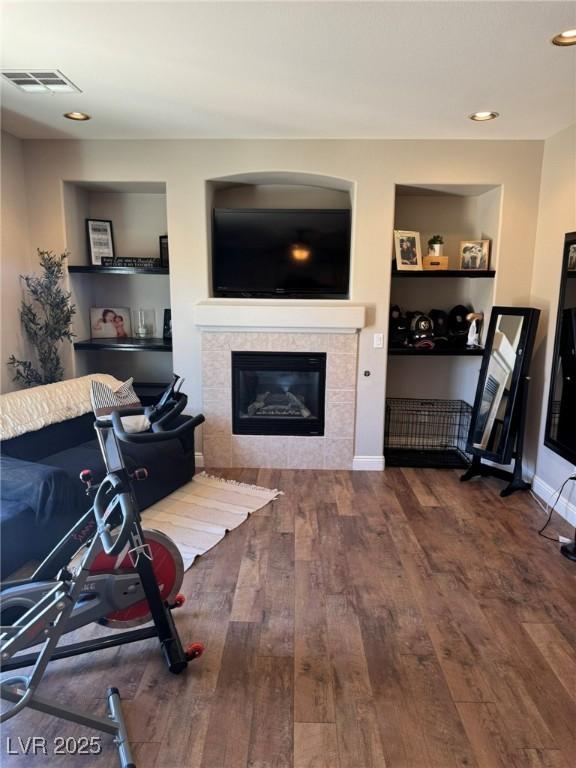 living area featuring a fireplace, recessed lighting, wood finished floors, and visible vents
