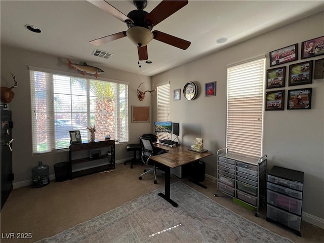 carpeted office space with baseboards, ceiling fan, and visible vents