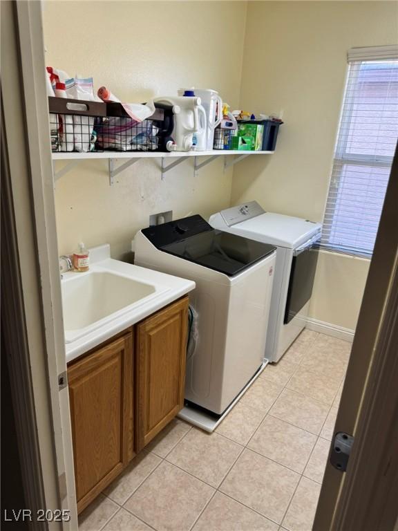 clothes washing area featuring a sink, cabinet space, light tile patterned floors, and washing machine and dryer