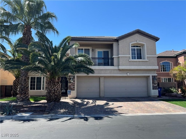 view of front of property with stucco siding, an attached garage, decorative driveway, and a balcony