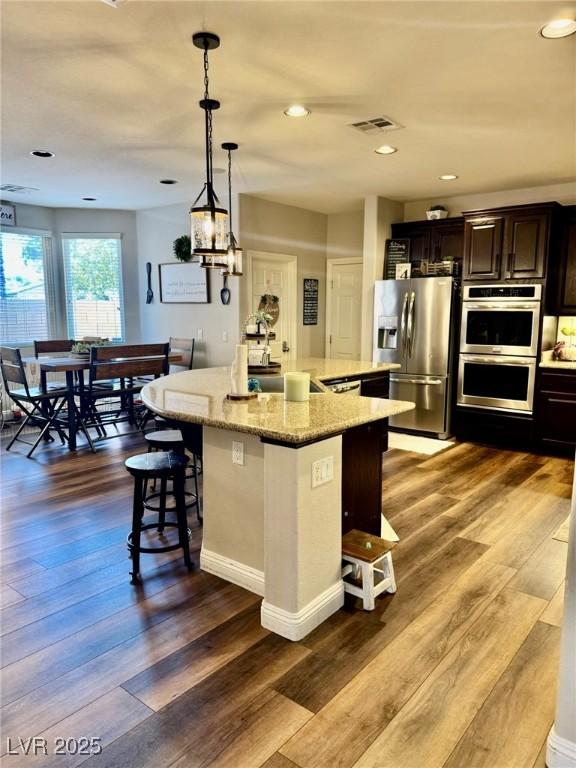 7109 Rancho De Taos, Las Vegas, NV 89130 - kitchen with appliances with stainless steel finishes, a breakfast bar area, a spacious island, a sink, and dark wood-type flooring
