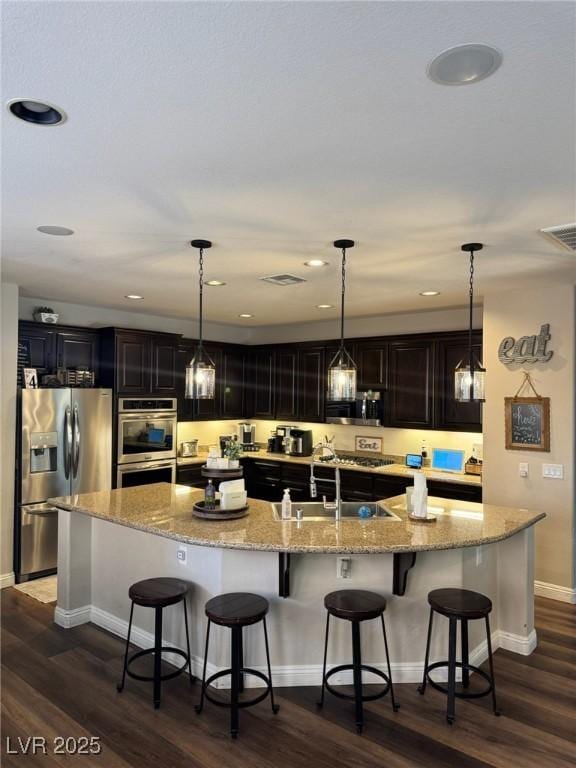 7109 Rancho De Taos, Las Vegas, NV 89130 - kitchen with appliances with stainless steel finishes, a large island with sink, dark wood-type flooring, a breakfast bar area, and recessed lighting