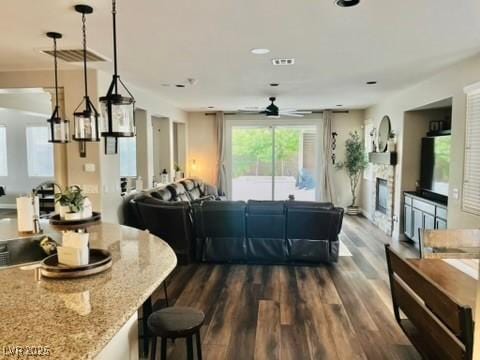 7109 Rancho De Taos, Las Vegas, NV 89130 - kitchen with open floor plan, a ceiling fan, dark wood-type flooring, light stone countertops, and a fireplace