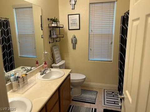 7109 Rancho De Taos, Las Vegas, NV 89130 - bathroom with tile patterned floors, toilet, double vanity, baseboards, and a shower with shower curtain