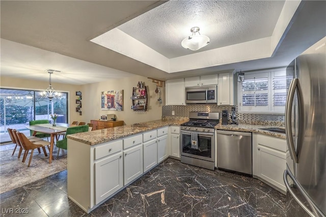 kitchen featuring backsplash, a peninsula, appliances with stainless steel finishes, and a healthy amount of sunlight