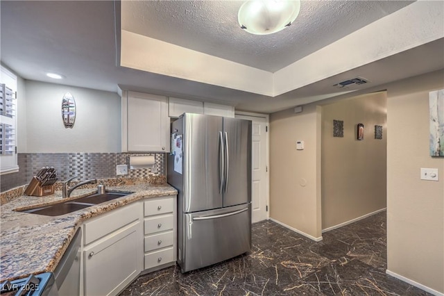 kitchen featuring a sink, baseboards, stainless steel appliances, and white cabinetry
