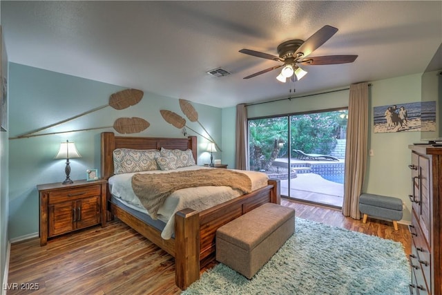 bedroom with access to exterior, a ceiling fan, baseboards, wood finished floors, and visible vents