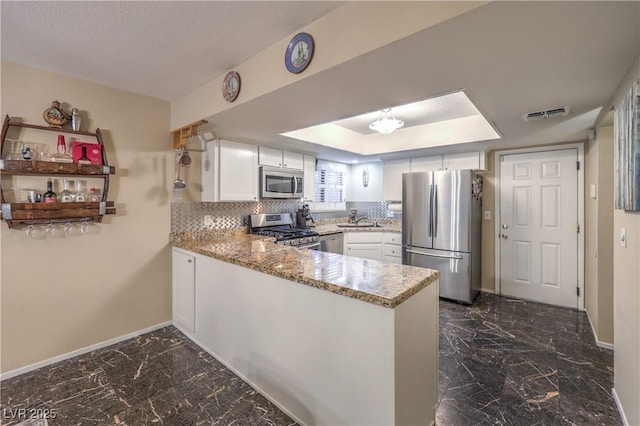 kitchen featuring visible vents, a peninsula, baseboards, a sink, and stainless steel appliances