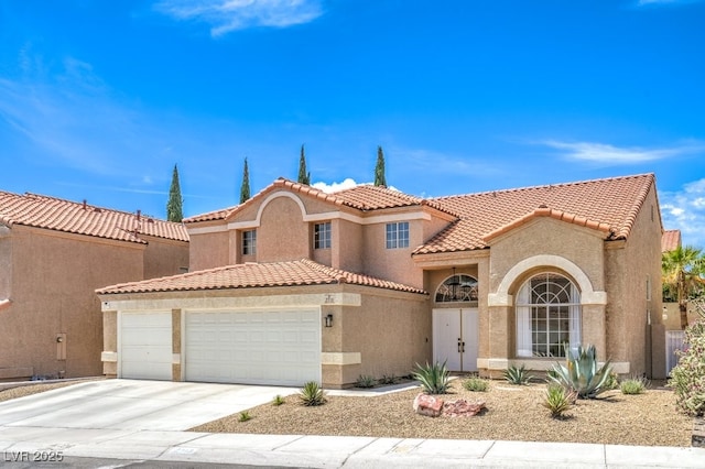 mediterranean / spanish-style home featuring an attached garage, concrete driveway, a tile roof, and stucco siding