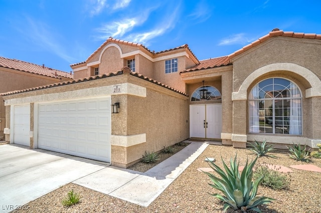 view of front of home featuring a garage, stucco siding, a tiled roof, and concrete driveway