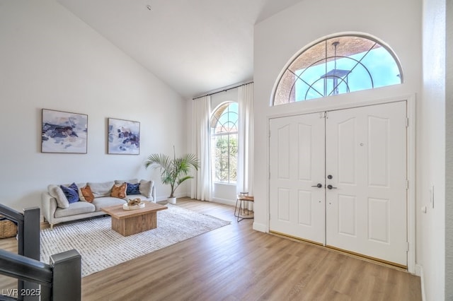 foyer entrance with high vaulted ceiling and light wood-style floors