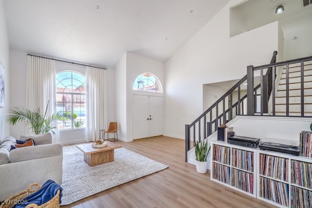 entrance foyer with high vaulted ceiling, plenty of natural light, stairs, and wood finished floors