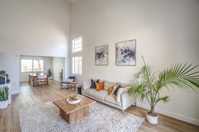 living room with baseboards, a notable chandelier, a wealth of natural light, and wood finished floors
