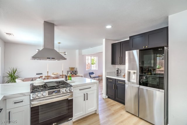 kitchen featuring visible vents, island range hood, appliances with stainless steel finishes, light wood-type flooring, and light stone counters