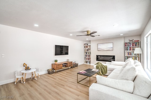living area featuring light wood-type flooring, a ceiling fan, baseboards, and recessed lighting