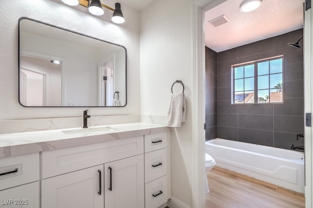 bathroom with visible vents, vanity, shower / bathtub combination, wood finished floors, and toilet