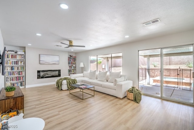 living area with a ceiling fan, visible vents, wood finished floors, and recessed lighting