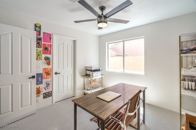 carpeted home office with ceiling fan and baseboards