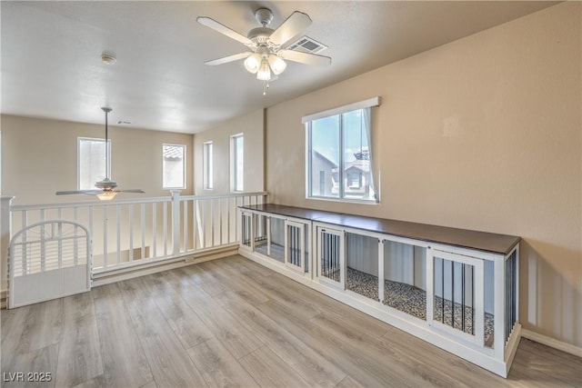 empty room with visible vents, a ceiling fan, and wood finished floors