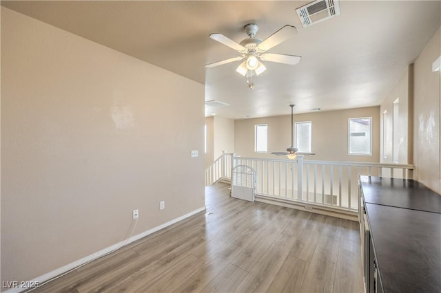 unfurnished room featuring ceiling fan, visible vents, a wealth of natural light, and light wood-style flooring