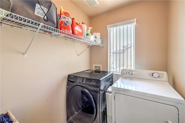 washroom featuring visible vents, laundry area, and washing machine and clothes dryer
