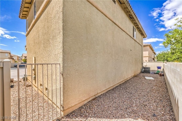 view of home's exterior featuring a fenced backyard, stucco siding, a gate, and central AC unit