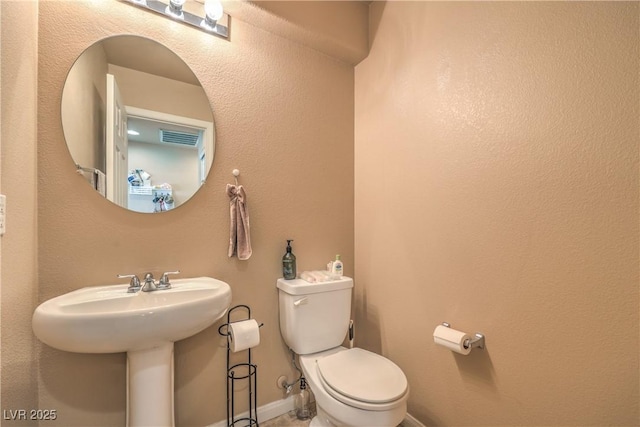 bathroom featuring a sink, baseboards, toilet, and visible vents