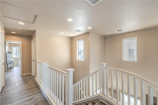 hallway featuring visible vents, recessed lighting, wood finished floors, and an upstairs landing